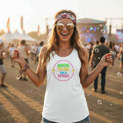 Smiling bride wearing white Bride To Be On A Spree tank top with neon design at outdoor music festival perfect for Nashville or Vegas bachelorette weekend White