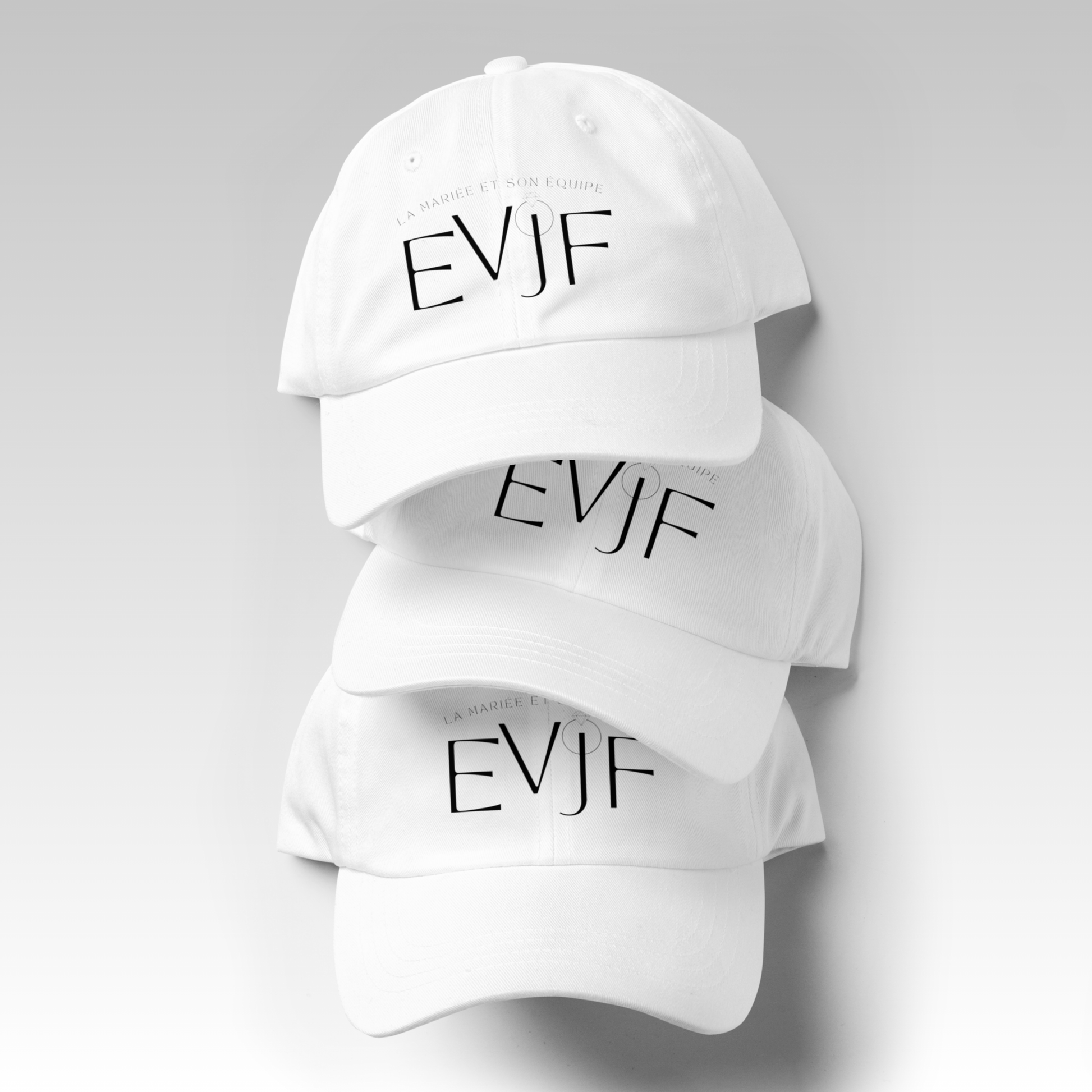 Plusieurs casquettes EVJF blanches avec broderie EVJF présentées empilées sur fond neutre.