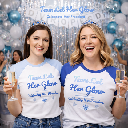 Two women celebrating at a divorce party wearing matching Team Let Her Glow t-shirts, raising champagne and celebrating her freedom together.