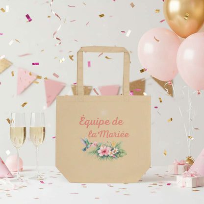 Tote bag beige Equipe de la Mariee avec design fleurs tropicales, accessoire parfait pour EVJF, bachelorette party, week end entre copines et celebration mariage.