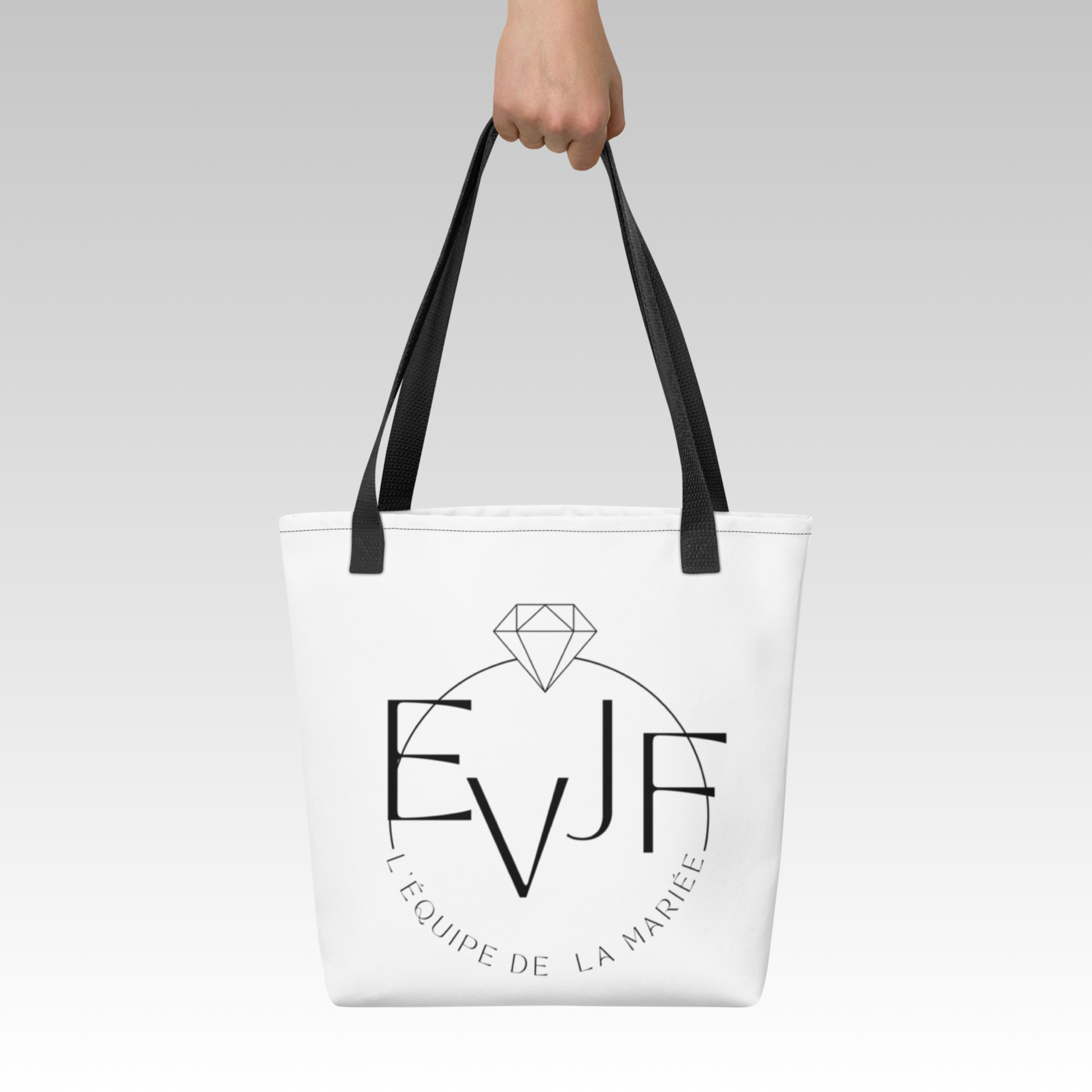 Tote bag EVJF blanc avec inscription équipe de la mariée porté à la main pour enterrement de vie de jeune fille