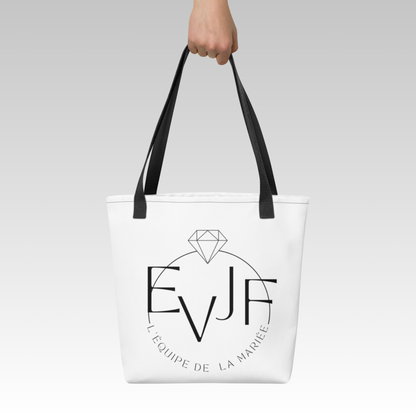 Tote bag EVJF blanc avec inscription équipe de la mariée porté à la main pour enterrement de vie de jeune fille