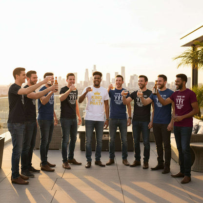 Group of men wearing EVG bachelor party t shirts including King of the Party and Groom Squad designs, celebrating enterrement de vie de garcon on rooftop with drinks and city skyline background.