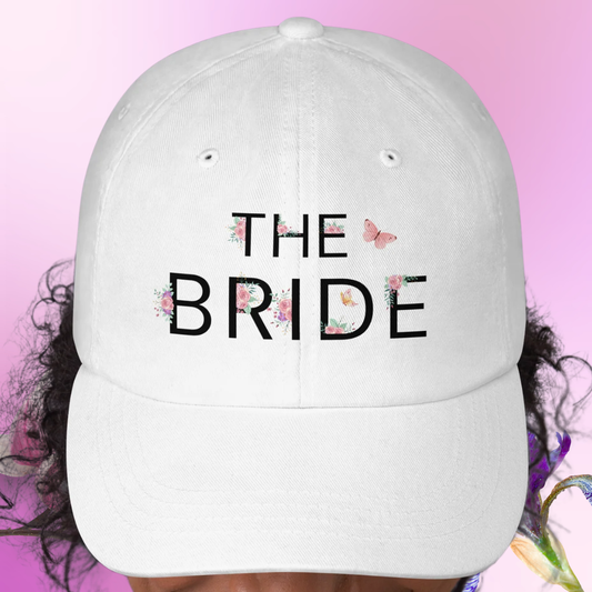 White embroidered The Bride cap worn on model, perfect accessory for bride during bachelorette party or wedding weekend.