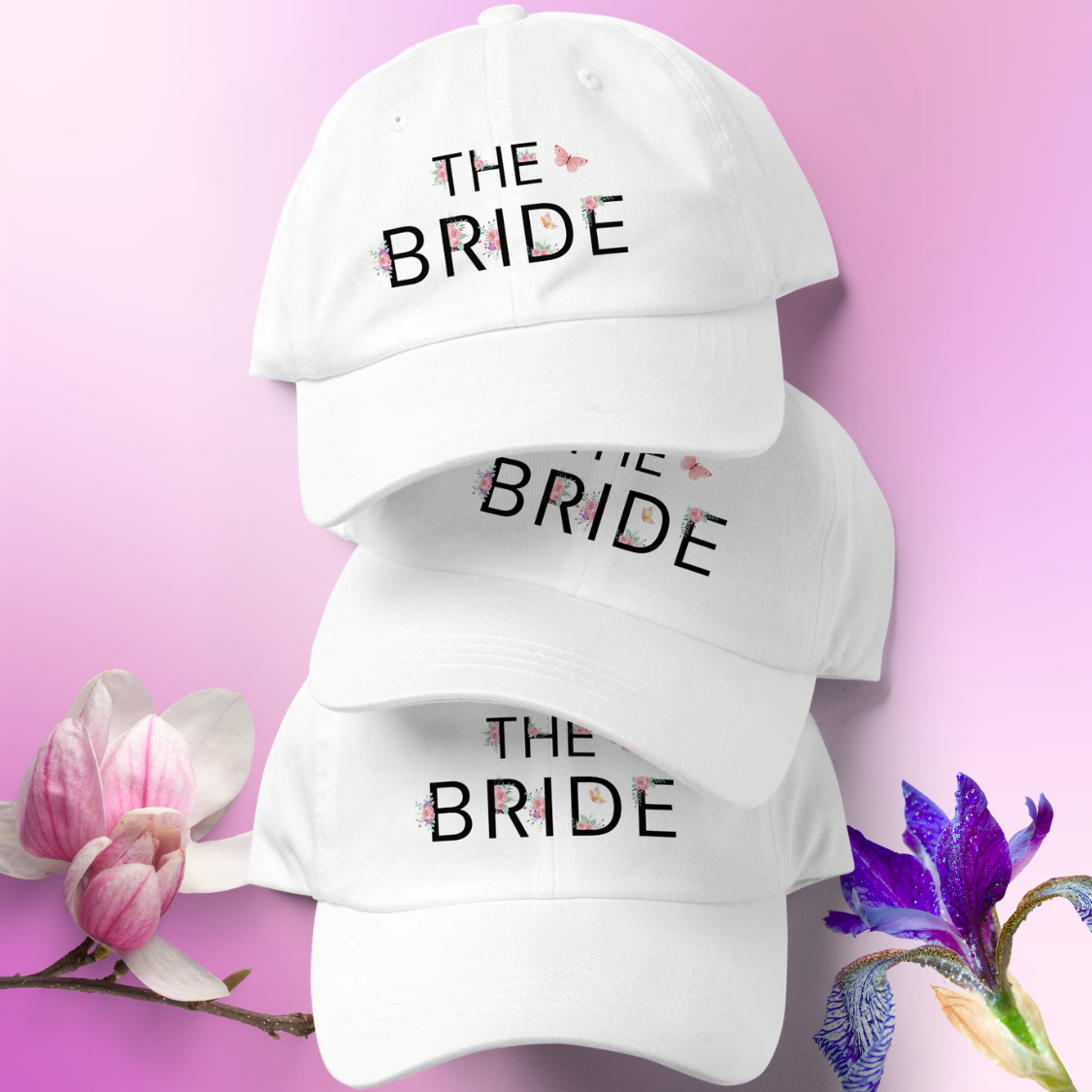 Stack of white embroidered The Bride caps with floral accents, ideal accessory for bride during wedding weekend or bachelorette party.