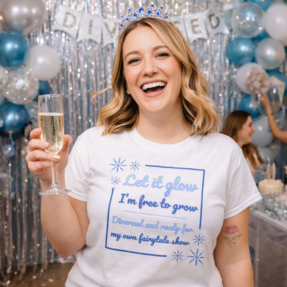 Smiling woman celebrating at a divorce party wearing Let It Glow t-shirt, raising champagne and enjoying a joyful freedom celebration.