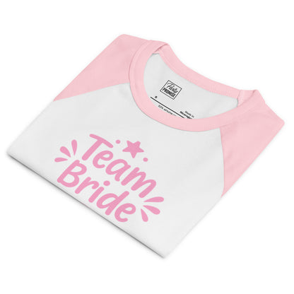 Close-up of the “Team Bride” raglan tee showing the micro-ribbed fabric and premium print. The bright white body and pink sleeves create a fresh Pink Party mood.